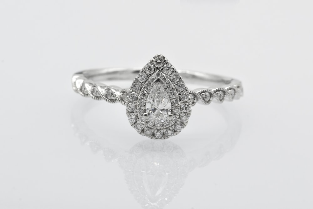 silver diamond studded ring on white surface