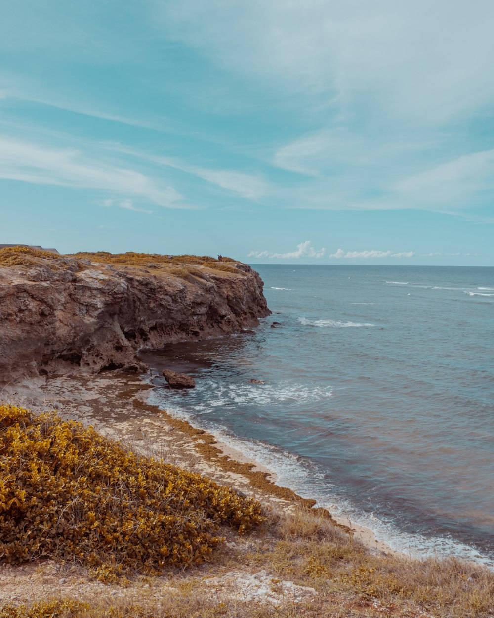 brown rock formation near sea under blue sky during daytime