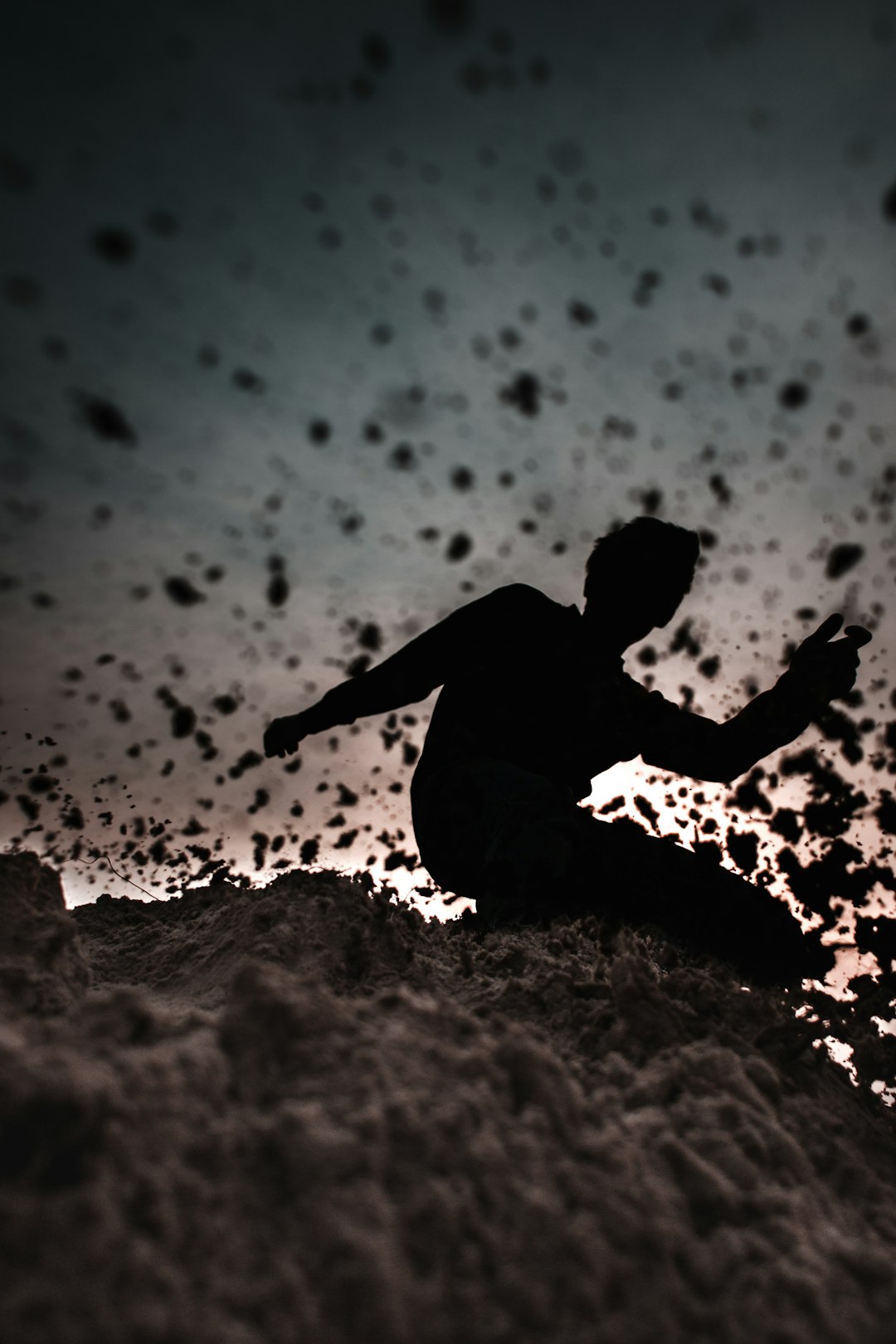 man in black shirt sitting on brown sand during daytime