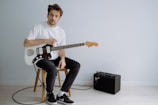 man in white crew neck t-shirt playing electric guitar