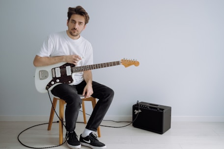 man in white crew neck t-shirt playing electric guitar