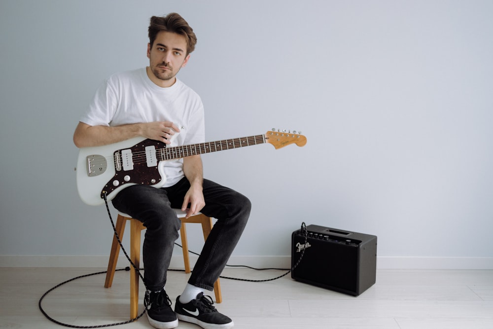 man in white crew neck t-shirt playing electric guitar