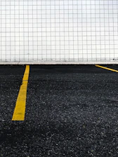 Close-up of bright yellow parking lot lines freshly painted on an asphalt surface.