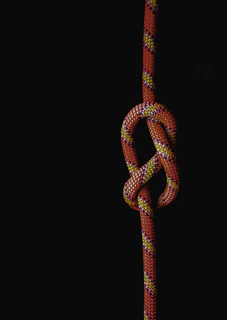 Close-up of an instructor tying a climbing knot with focused students watching