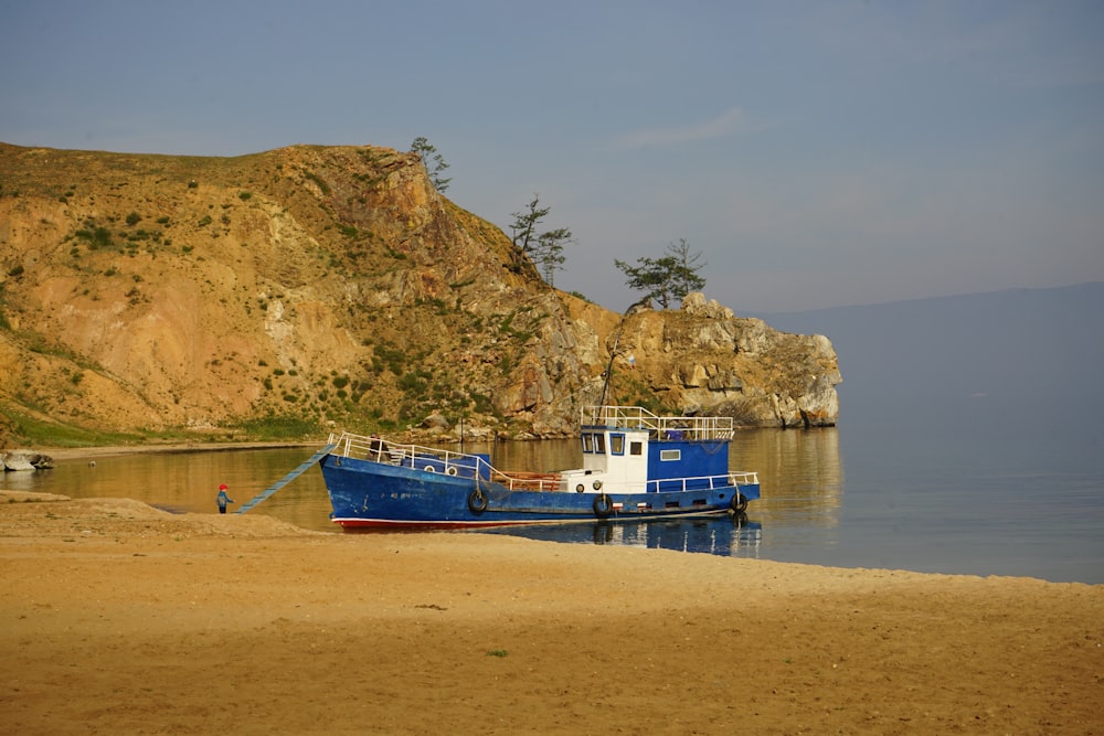 blue and white boat on sea shore during daytime