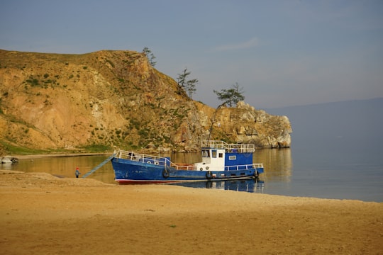 blue and white boat on sea shore during daytime in Olkhon Island Russia