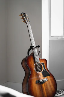 A close-up of a handcrafted wooden guitar resting against a rustic wall, sunlight highlighting its rich grain.