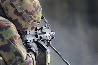 man in green and brown camouflage uniform holding rifle