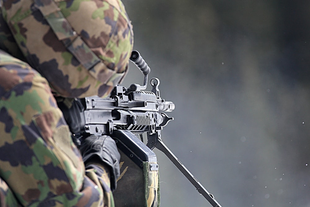 man in green and brown camouflage uniform holding rifle