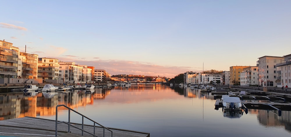 body of water near city buildings during sunset