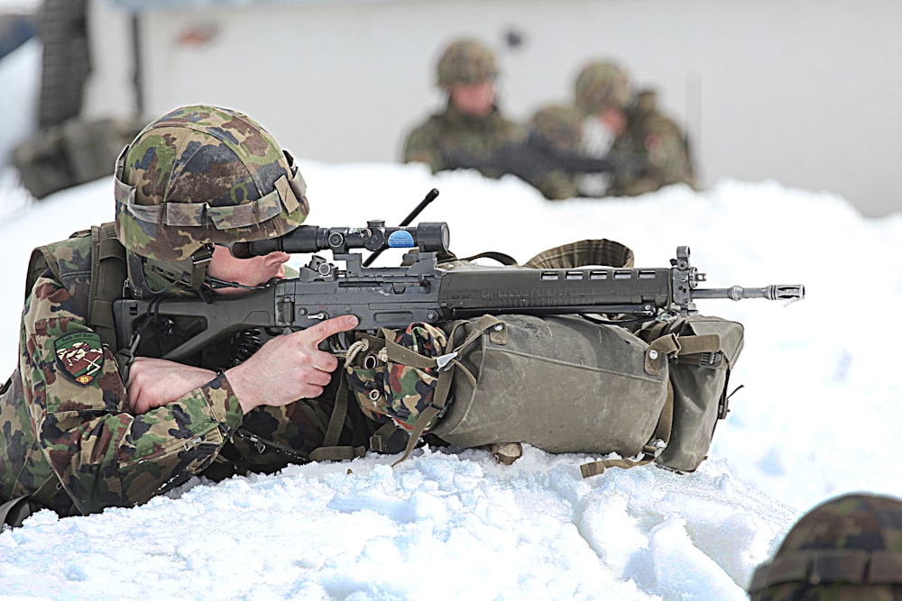 Hombre con traje militar de camuflaje verde y marrón sosteniendo un rifle