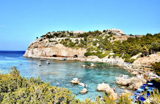 green and brown mountain beside blue sea under blue sky during daytime