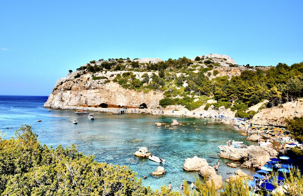 green and brown mountain beside blue sea under blue sky during daytime