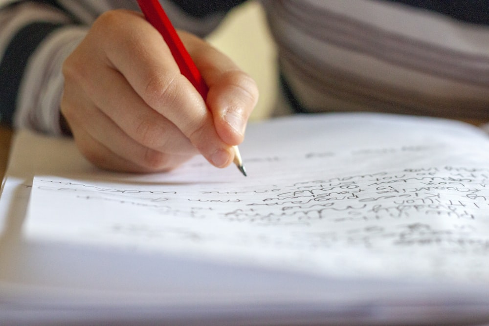 personne écrivant sur du papier blanc