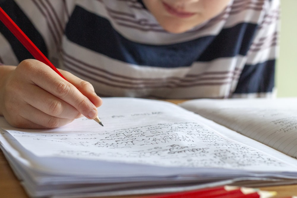 personne écrivant sur du papier blanc