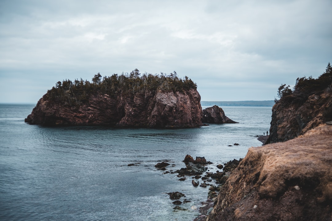 brown rock formation on blue sea under white clouds during daytime