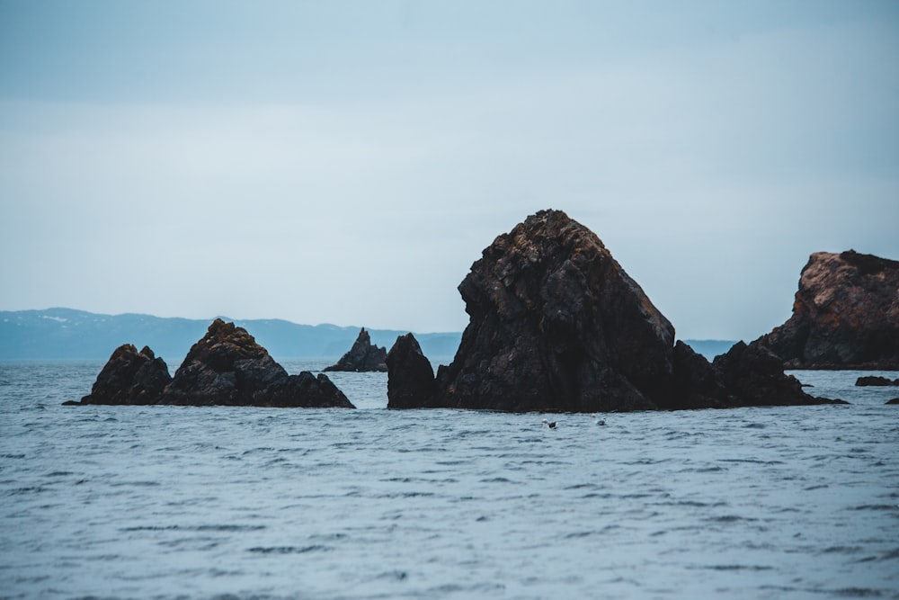 black rock formation on sea under white sky during daytime