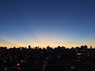 Evening city skyline glowing with golden lights against a deep black sky.