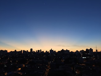 Evening city skyline with financial district buildings lit up in deep navy blue and gold hues.