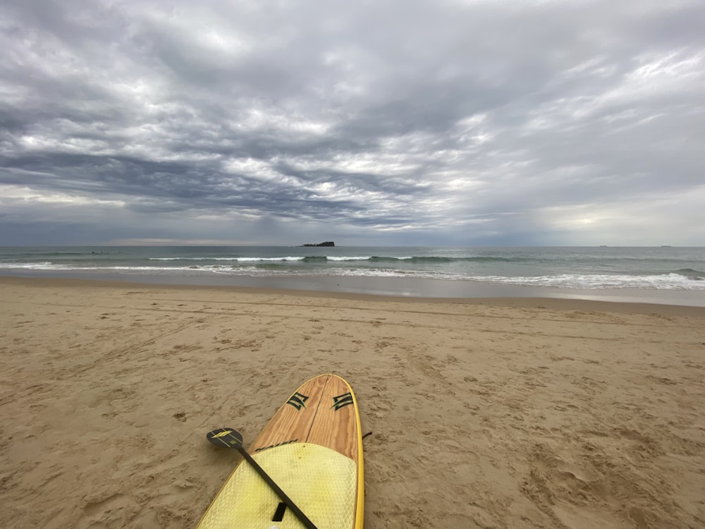 gelbes und braunes Surfbrett tagsüber am Strand