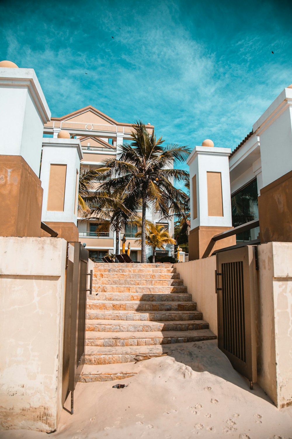 white concrete building near palm trees under blue sky during daytime