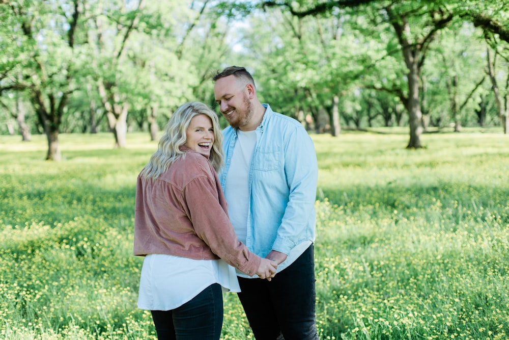 man and woman standing on green grass field during daytime