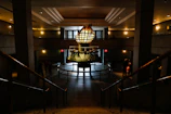 Grand entrance hall with a towering sculpture anchoring the space, surrounded by neutral tones and soft lighting.