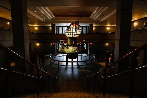 Grand entrance hall with a towering sculpture anchoring the space, surrounded by neutral tones and soft lighting.