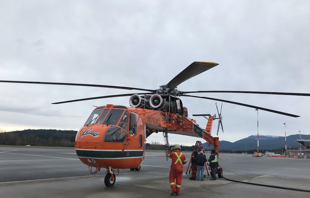 people in orange helicopter during daytime