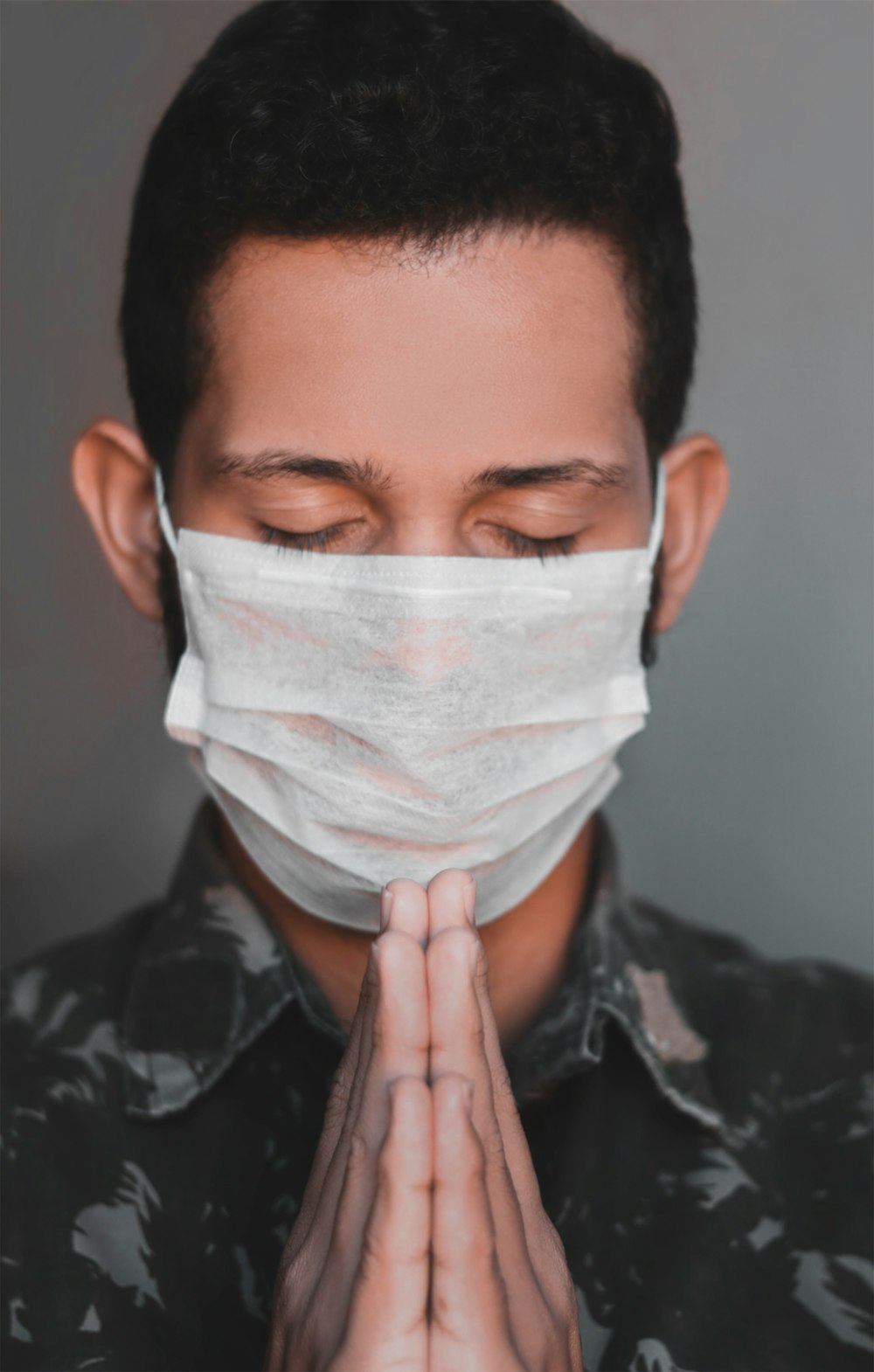 man in black and gray camouflage jacket covering his face with white paper