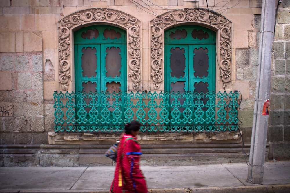 woman in red and blue dress walking on sidewalk during daytime