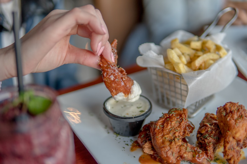 person holding white ceramic plate with fried food