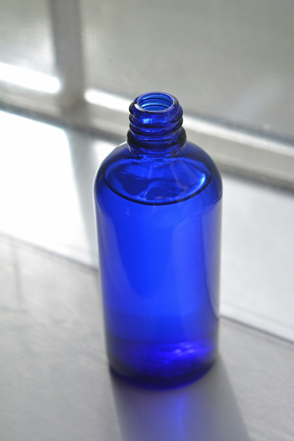 bouteille en verre bleu sur table blanche
