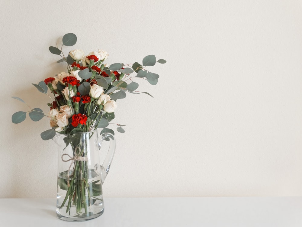 red and white flowers in clear glass vase