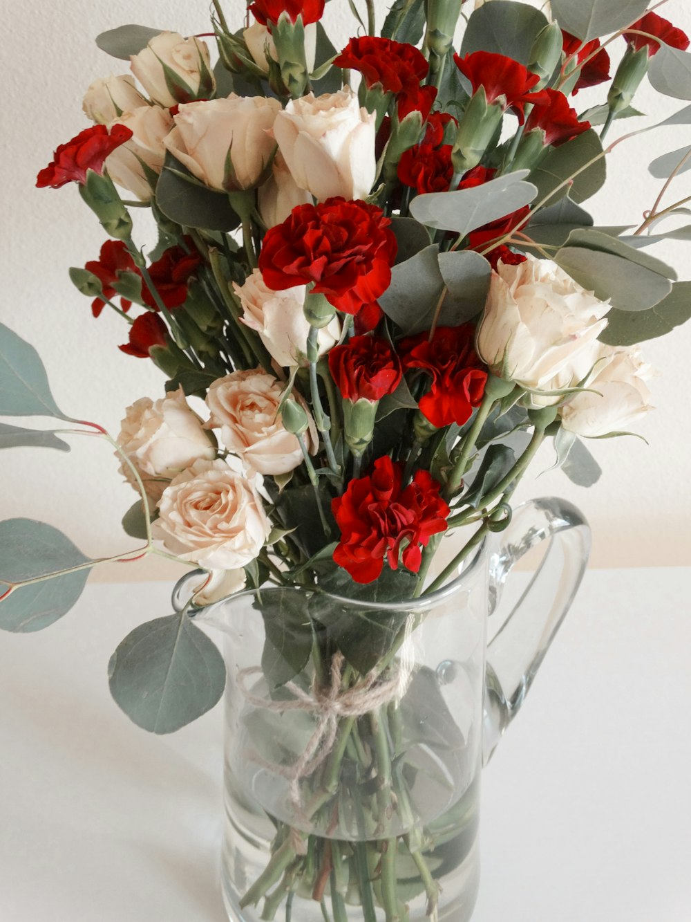 white and red roses in clear glass vase