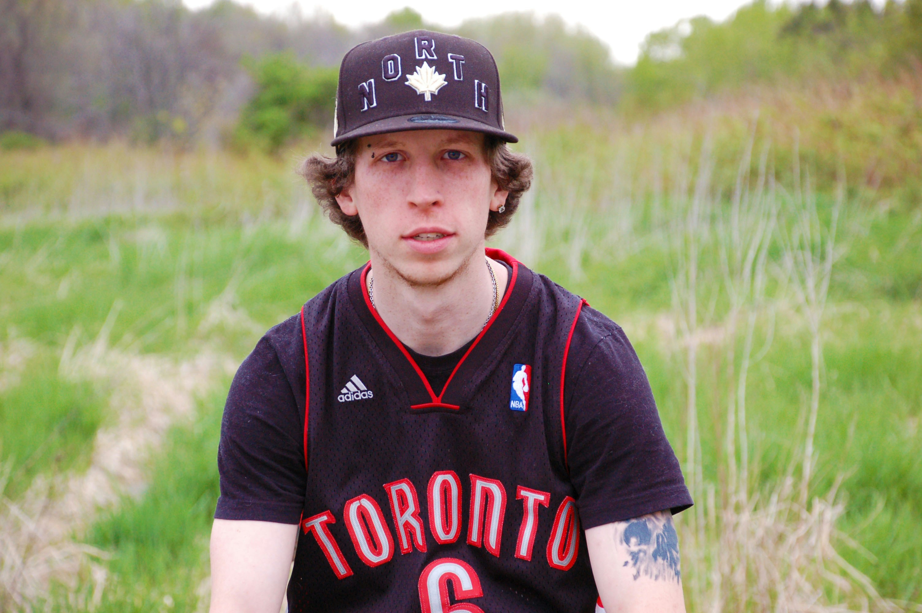 a young man with a baseball cap sitting in a field