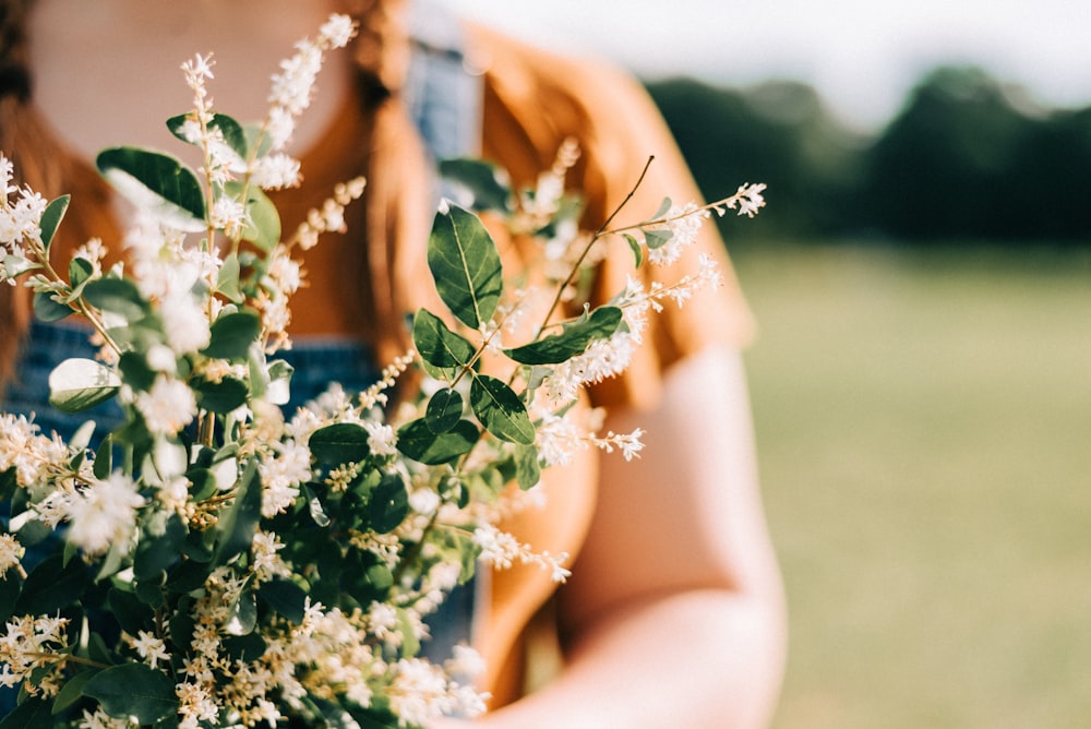 woman in white floral dress holding white flowers