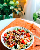 A vibrant salad with roasted squash, cranberries, and toasted nuts in a ceramic bowl.