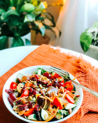 A vibrant salad with roasted squash, cranberries, and toasted nuts in a ceramic bowl.