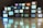 A collection of vintage television sets are stacked upon each other, each displaying static or random color bandwidth. These TVs create an artistic installation with reflections visible on the polished floor, presenting a nostalgic and retro aesthetic.