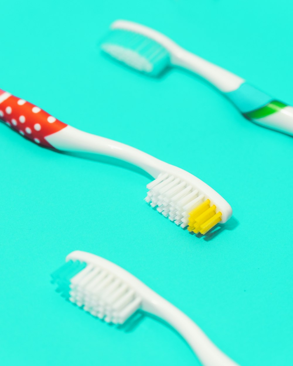 white and green toothbrush on teal surface