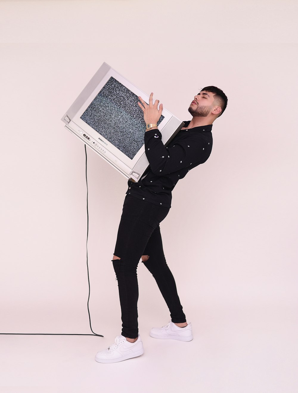 man in black jacket and black pants holding white laptop computer