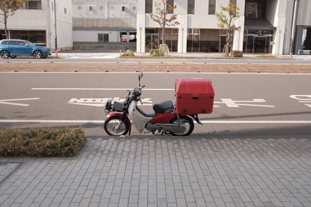 red and black motorcycle parked on sidewalk during daytime