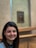A smiling woman admiring a painting in a gallery.