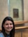 A smiling woman standing in front of a vibrant painting by Lady Natalia Pérez.