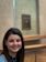 A smiling woman admiring a painting in a gallery.