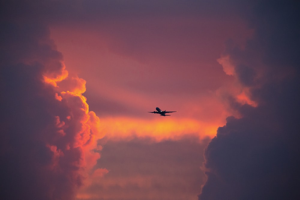 airplane flying in the sky during sunset