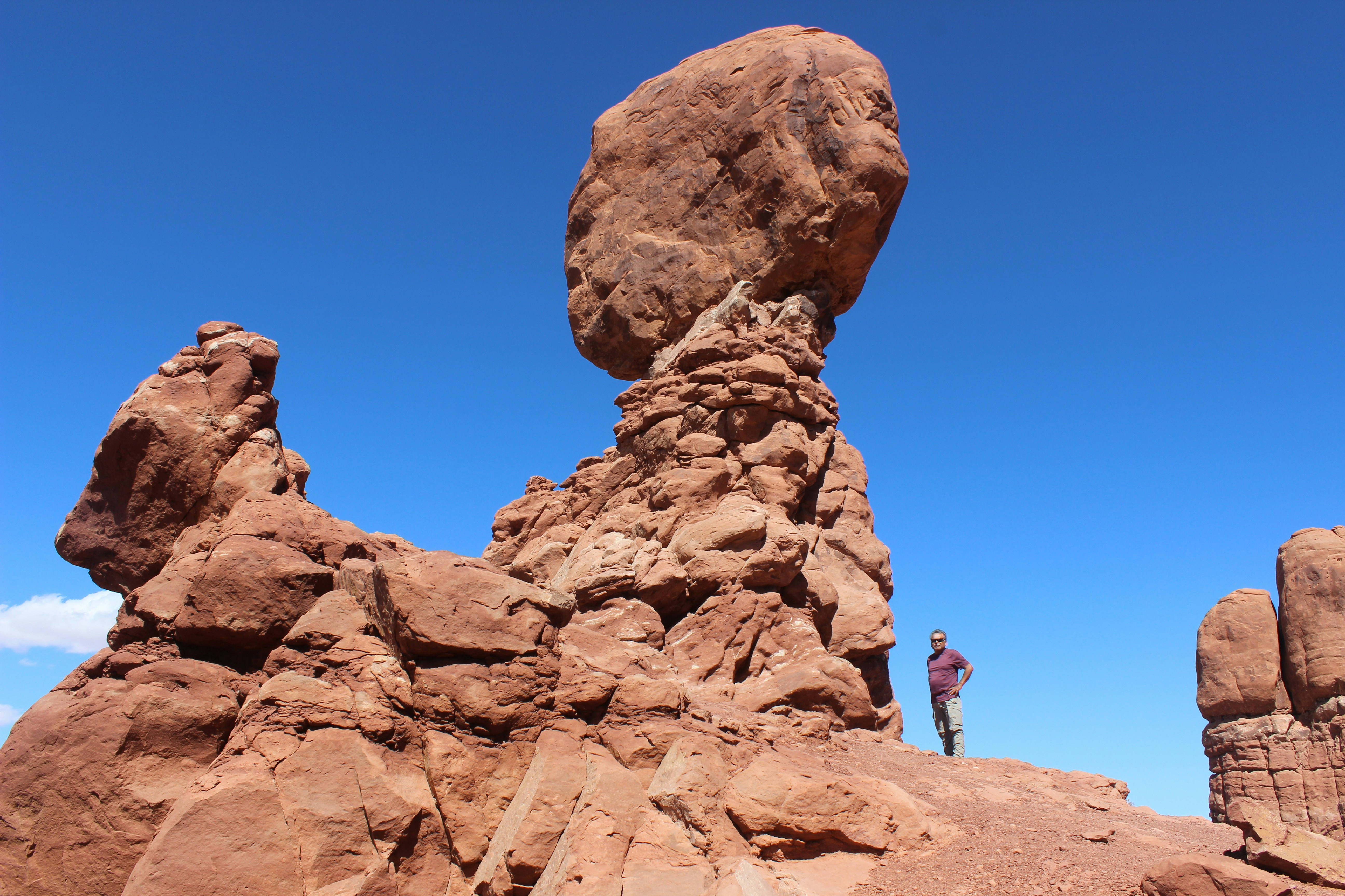 person standing on brown rock formation under blue sky during daytime