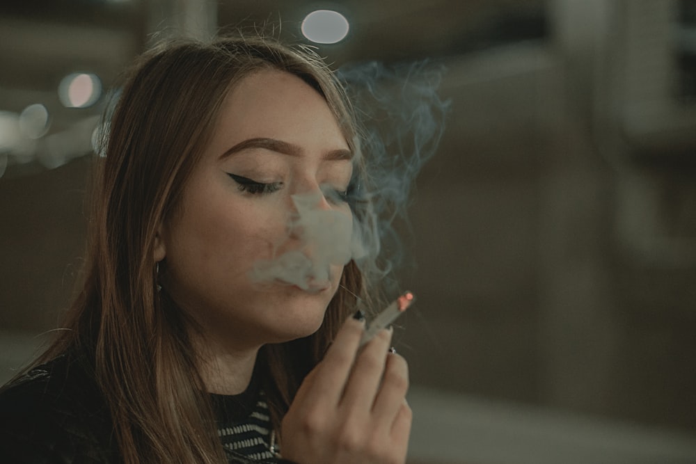 Mujer en camisa a rayas blancas y negras fumando cigarrillo
