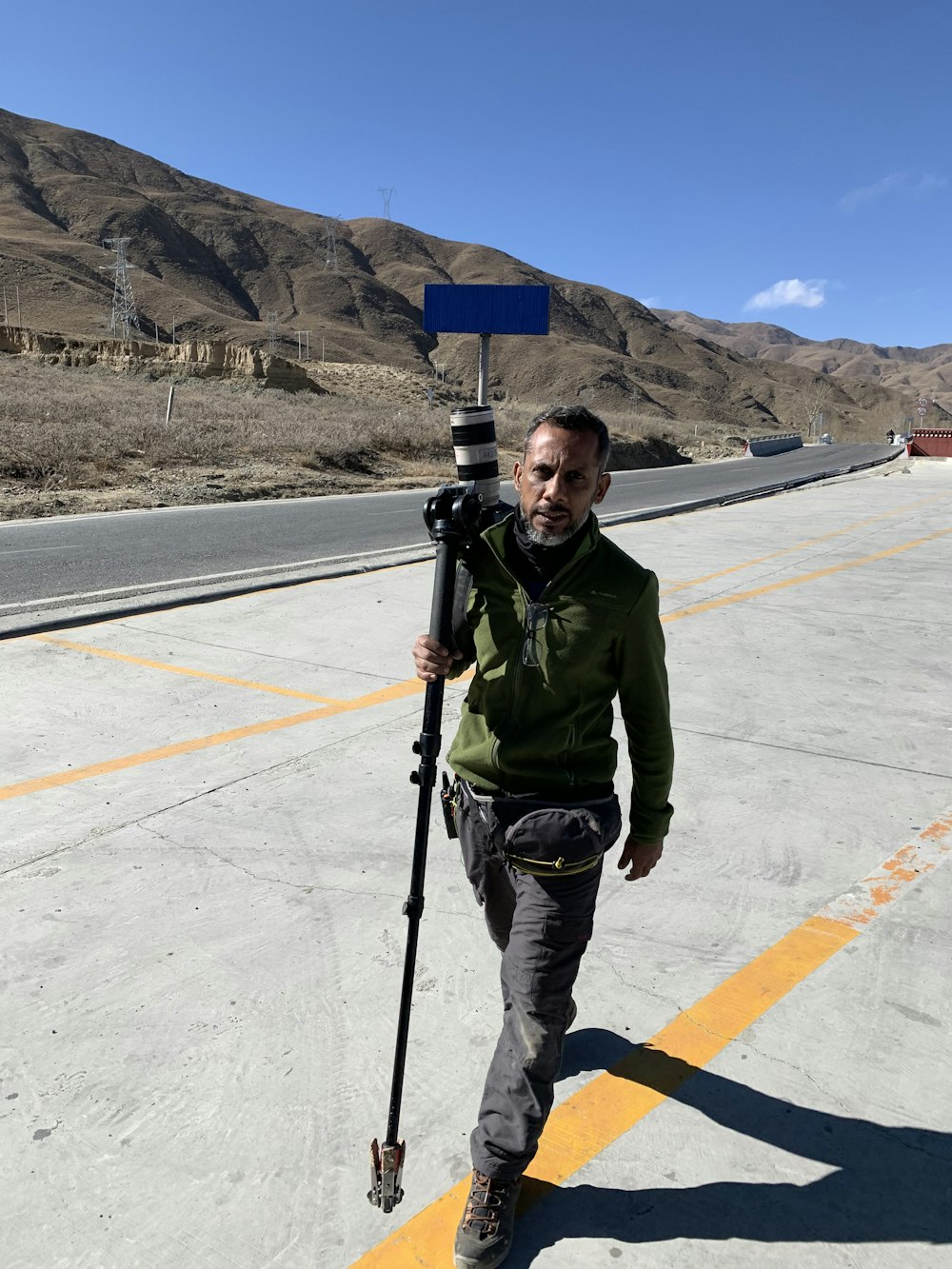 a man walking down a road with a camera on his shoulder